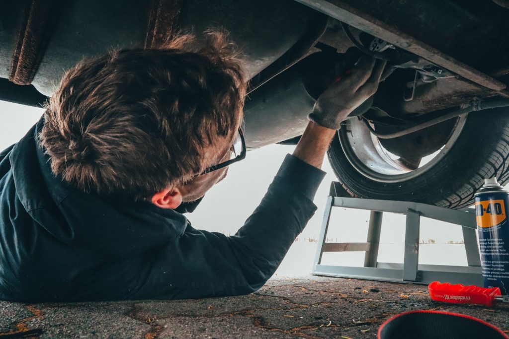Mechanic wearing glasses on the floor under a car