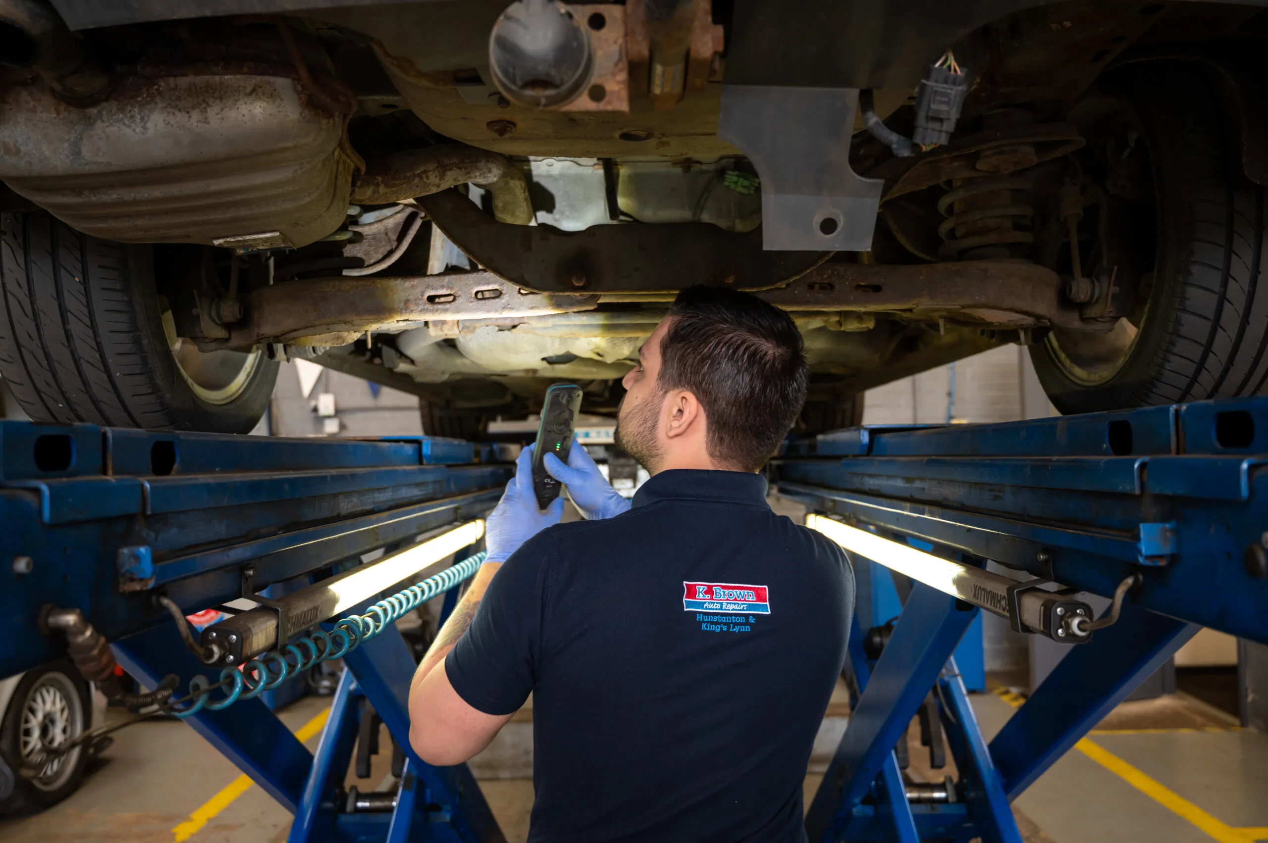 Technician inspecting under car