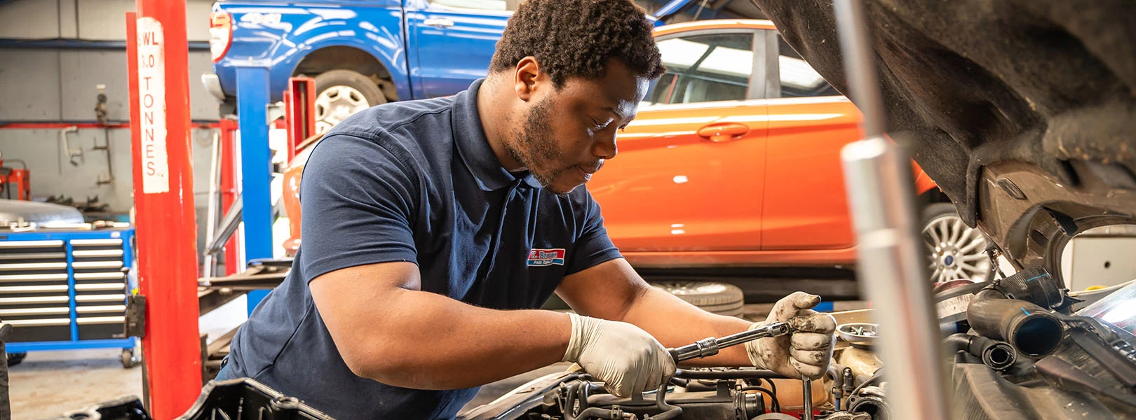 Technician working under bonnet of car