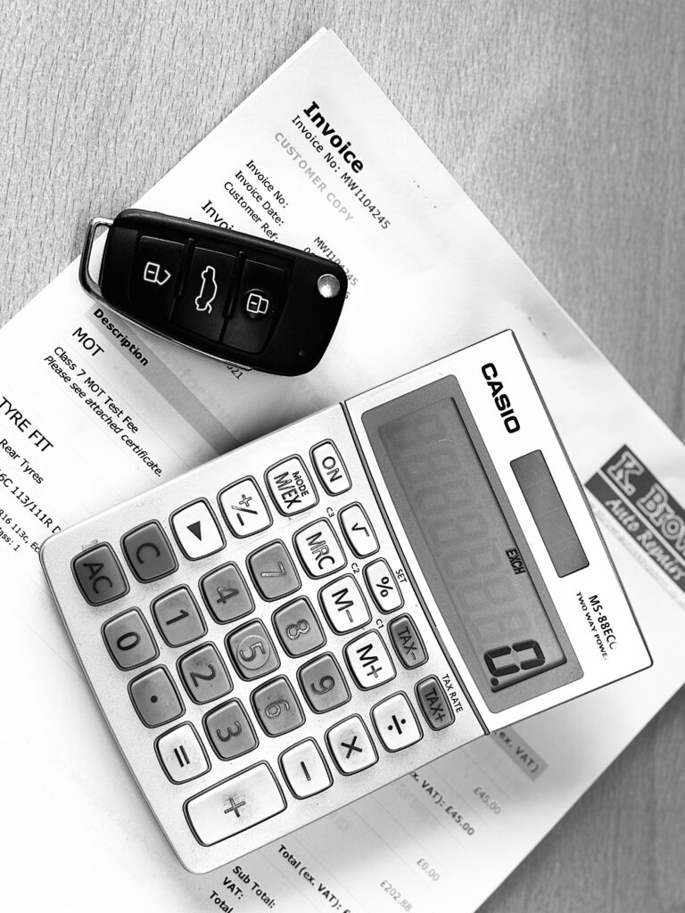 Car keys and calculator sitting on top of a K Brown Auto Repairs invoice
