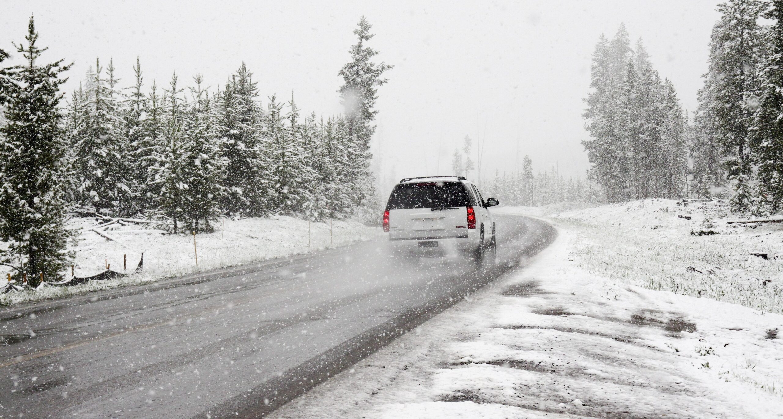 White car driving on the road in the snow 